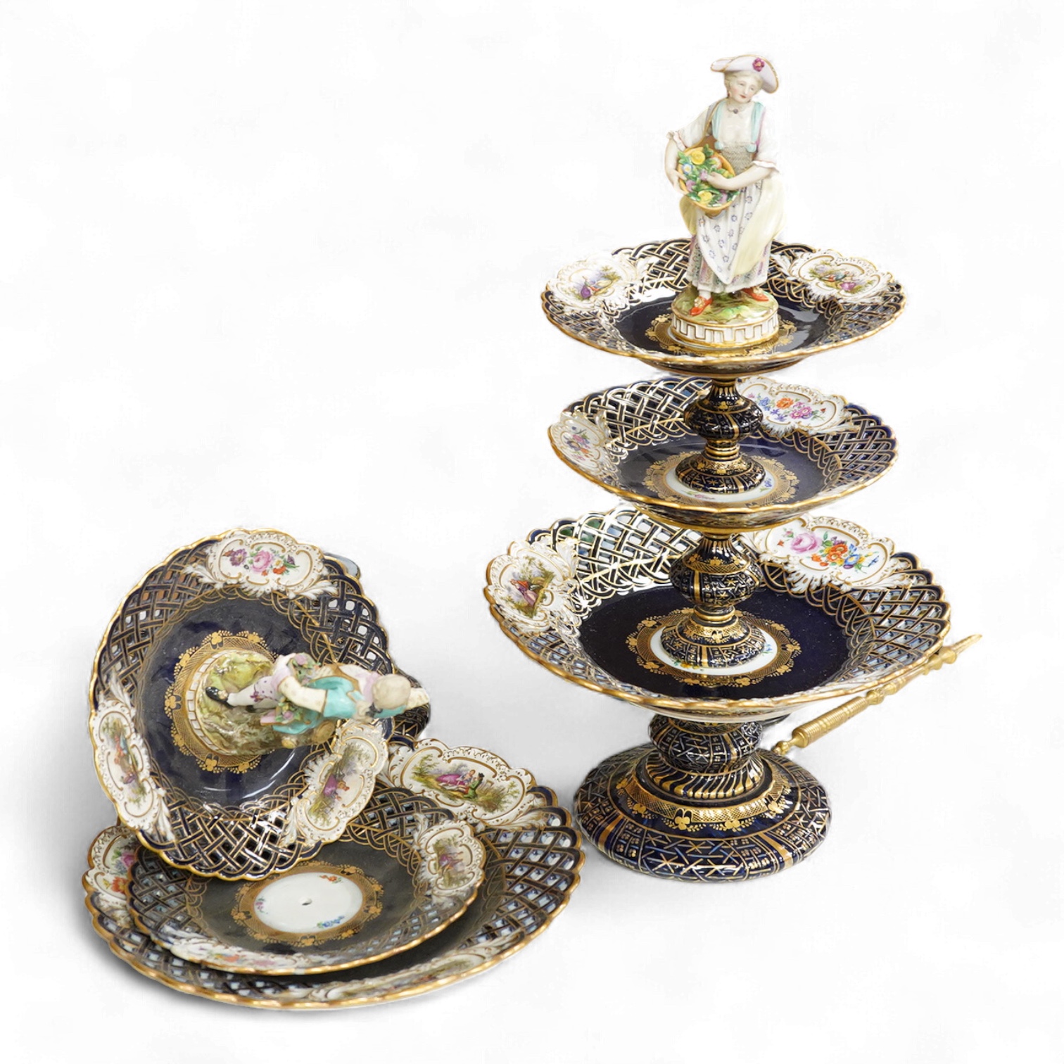 A pair of late 19th century Meissen three tier cake stands with figural tops, 48cm high